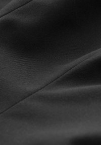 Czarna tkanina o gładkiej, matowej teksturze; zawiera subtelne ukośne linie i fałdy, prezentując elegancki i jednolity wygląd.