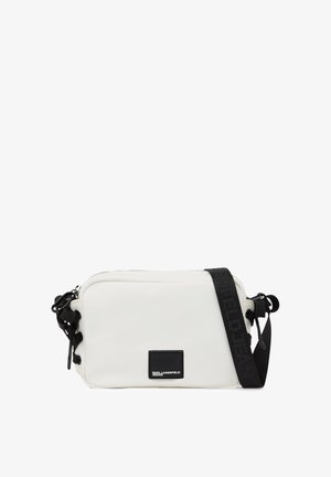 Bolso bandolera rectangular blanco con correa ajustable negra y parche de logo negro que dice "Karl Lagerfeld Jeans" en el frente.