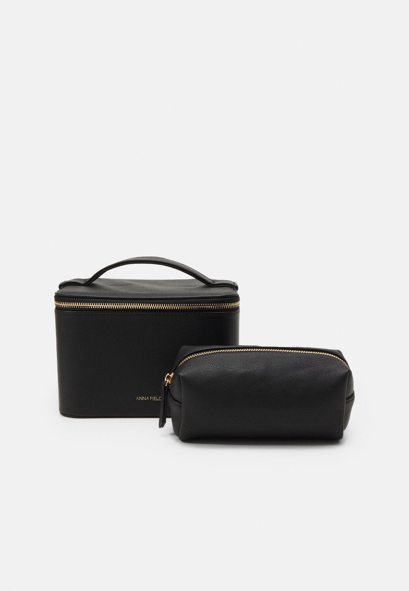 Conjunto de nécessaire de couro preto, apresentando um estojo retangular com alça e uma bolsa cilíndrica, ambas com fechos e detalhes em dourado.