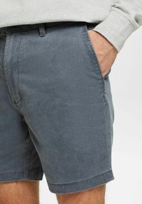 Grå bomulds-shorts med en glat tekstur, sidelommer og stikninger i kanten, der har en afslappet pasform og et afslappet design.