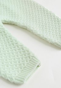 Megztas šviesiai mėtinės žalumos viršus, puoštas tekstūruotu rombų raštu su ribinėmis rankogaliais. Minkšta siūlų medžiaga su švelniai pūkuota apdaila.