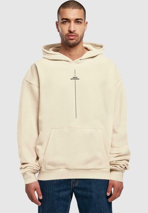 Beige hætteSweatshirt med en frontlomme, prydet med en vertikal sort tekstgrafik. Fremstillet af blødt stof med en afslappet pasform.