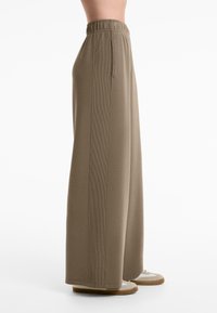 Wide-leg pants in khaki fabric; features an elastic waistband, vertical ribbed accents, and cuffed hem. Soft, smooth texture.