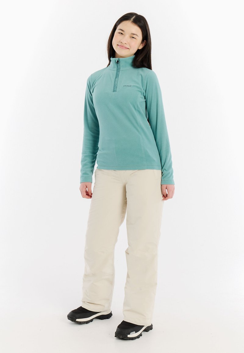 Teal fleece pullover met een kwart-rits, lange mouwen en een hoge kraag, gecombineerd met beige skibroeken en zwarte winterlaarzen.