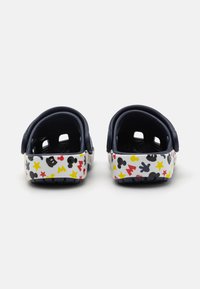 Navy blue back strap clogs with a white sole showcasing colorful patterns of cartoon characters and stars. Rounded design with ventilation holes.