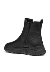 Botas de tobillo negras de cuero suave con cremallera lateral, puntera redondeada y suela de goma gruesa con patrones en forma de onda.