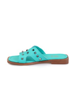 Turquoise slide sandalen met een platte bruine zool, voorzien van metalen studs op de bovenkant en een open ontwerp voor ademend vermogen.