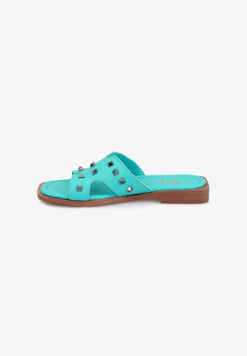 Turquoise slide sandalen met een platte bruine zool, voorzien van metalen studs op de bovenkant en een open ontwerp voor ademend vermogen.