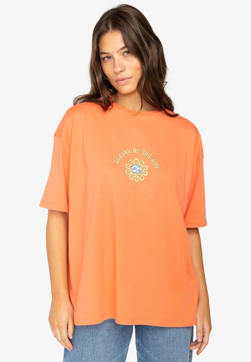 Oranje oversized t-shirt van katoen, met een cirkelvormig zonlogo in goud en blauw op de middel. Korte mouwen en ronde hals.
