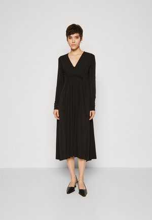 Black long-sleeve dress with a V-neck, fitted bodice, pleated skirt, and drawstring waist. Smooth fabric with a flowing silhouette.