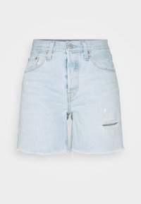Shorts en denim bleu clair avec un ourlet effiloché, présentant une déchirure sur la jambe gauche et un design classique à cinq poches.