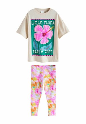 Beige T-shirt med stor lyserød blomst og teksten "Wild Flora Beach Cafe" kombineret med farverige leggings i pastelfarver med blomstermønster.