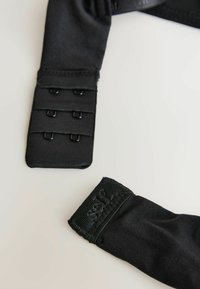 Čierne elastické popruhy s nastaviteľnými háčikmi a očkami. Mäkká textúra a pevné švy, s logom blízko koncov.