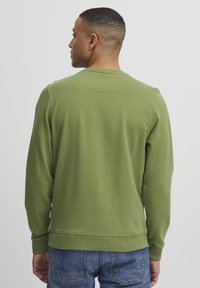 Groene sweatshirt met lange mouwen, ronde hals en geribbelde manchetten. Zachte, geweven stof, gestyled met een rechte snit en een klein labeldetail aan de zijkant.