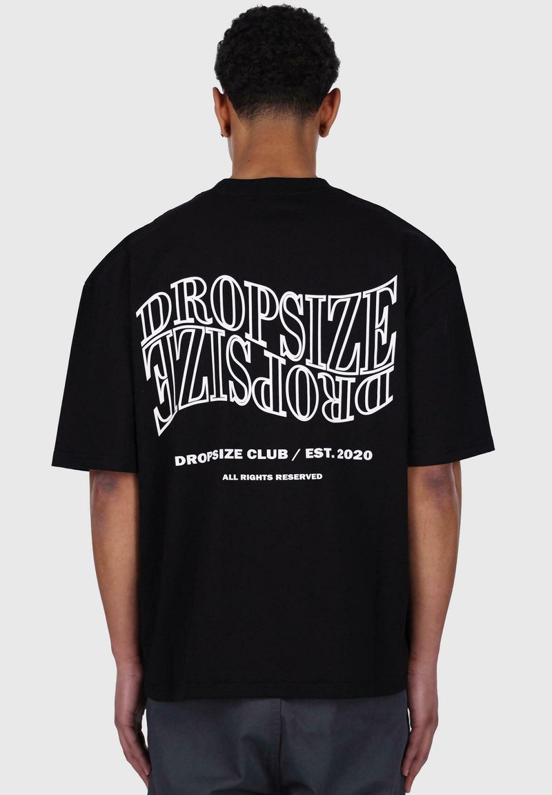 Crna pamučna majica s velikim bijelim natpisom na leđima. Dizajn uključuje "DROPSIZE" i "DROPSIZE CLUB / EST. 2020." Kratki rukavi.