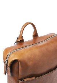 Tan leather bag with top handle and visible zipper closure, showing detailed stitching and smooth texture on a white background.