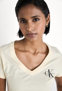 Calvin Klein Jeans MONOLOGO V NECK TEE - Triko s potiskem - vanilla