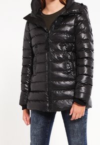 Chaqueta negra acolchada con un acabado brillante, zipper frontal, capucha y bolsillos laterales. Presenta un acolchado horizontal y puños acanalados.