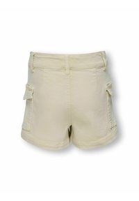 Beżowe szorty bawełniane z dwoma kieszeniami cargo po bokach, dopasowaną talią i podwiniętym dołem. Tkanina ma gładką teksturę i swobodny fason.