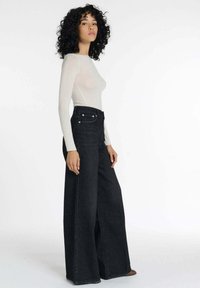 Zwarte wijde jeans met hoge taille, voorzien van een klassiek vijf-pocket ontwerp en zilverkleurige hardware, gecombineerd met een aansluitend longsleeve shirt.