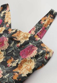 Haut en tissu à motifs floraux avec bretelles ajustables. Présente de grandes roses éclatantes en rose, orange et crème sur un fond noir. Texture douce.