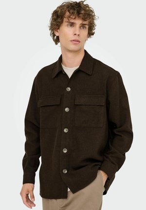 Brown, button-up shirt in soft material with two chest pockets, a pointed collar, and a relaxed fit. Features contrasting buttons and long sleeves.