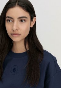 Marineblauer Sweatshirt mit Rundhalsausschnitt, ausgestattet mit einem strukturierten Logo in passender Farbe. Weiches Baumwollmaterial, lockere Passform und sichtbare Nähte.