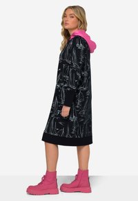 Marinefarbene Kapuzenkleid mit weißem Segelbootmuster, gerippten Bündchen und Saum. Kombiniert mit leuchtend pinken Schnürkampfstiefeln.
