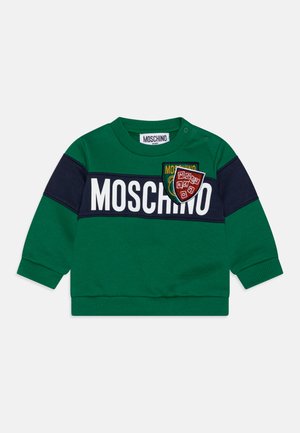 Maglione verde in cotone con strisce blu, con grande testo bianco "MOSCHINO" e una toppa a scudo ricamata sul petto. Dettagli con bottoni a pressione.