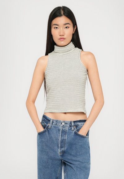 Striped sleeveless turtleneck top in cream and black, made of soft fabric. Cropped design with a fitted silhouette.