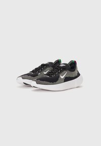 Sorte strikede sportsko med en hvid sål, prydet med grønne og lilla detaljer samt et struktureret design med et fremtrædende Nike swoosh-logo.