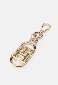 Breloc din metal auriu cu un design proeminent al unui logo interconectat, având un clips de homar și detalii cu linkuri de lanț pentru prindere.