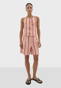 Gestreepte mouwloze top en short set, met roze en koraalstrepen, gemaakt van een lichtgewicht stof, compleet met zwarte teenslippers.