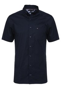 Camisa de manga corta color azul marino oscuro, hecha de algodón. Cuenta con un cuello puntiagudo, botones en la parte delantera y un pequeño bolsillo en el pecho.
