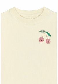 Krämbelagd bomullströja med en grafisk bild av två leende körsbär med rosa skal och gröna blad, rund halsringning och korta ärmar.