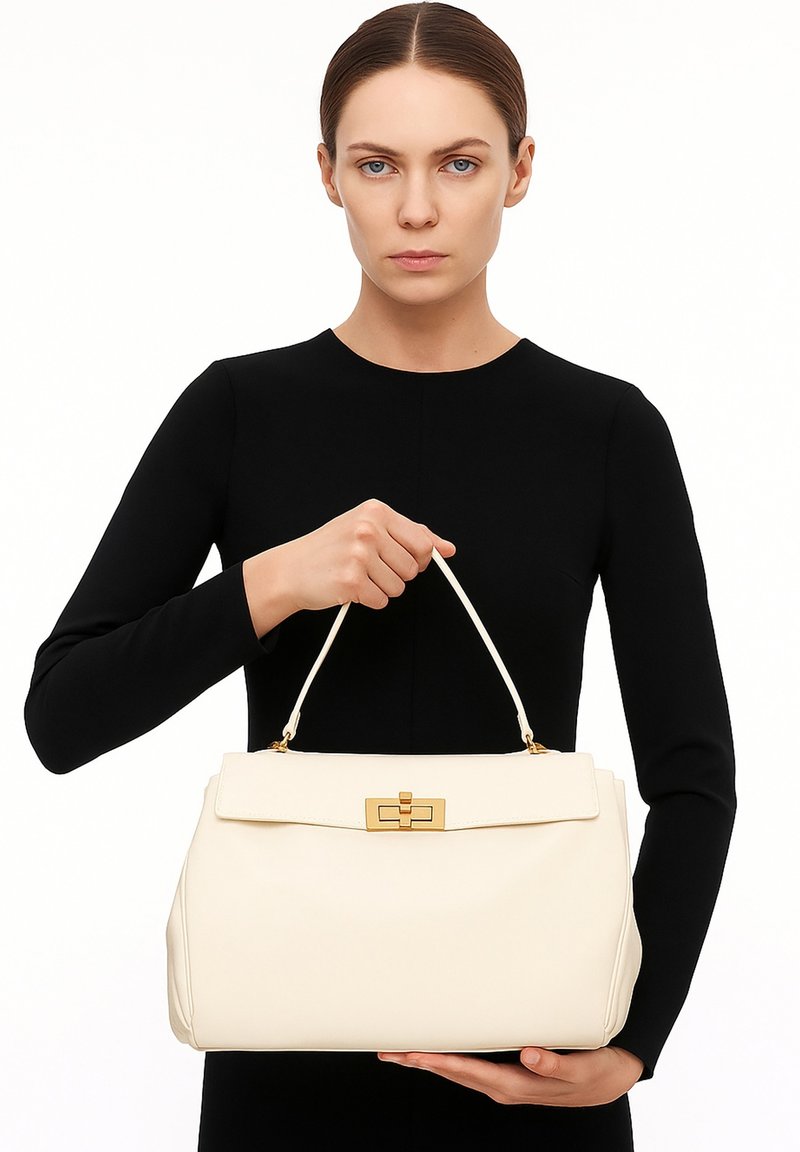 Borsa a mano in pelle crema con forma strutturata, manico superiore, accessori in oro e chiusura a patta. Texture liscia con dettagli sottili.