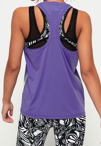 Top sportivo viola con design a schiena scoperta, caratterizzato da dettagli in stampa zebra in bianco e nero sulle spalle e ai lati.