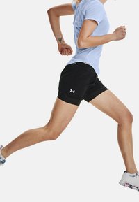 Czarne sportowe szorty wykonane z lekkiego materiału, z boczną kieszenią i logo. Model nosi jasnoniebieską bluzkę i buty do biegania.