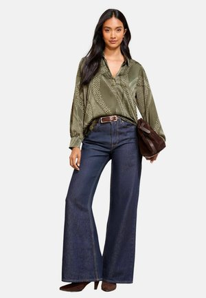 Olive green patterned blouse with a loose fit, paired with high-waisted dark blue wide-leg jeans, brown belt, and a brown suede handbag.