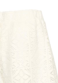 Jupe en dentelle blanche avec ceinture élastique présentant des motifs géométriques et floraux découpés.