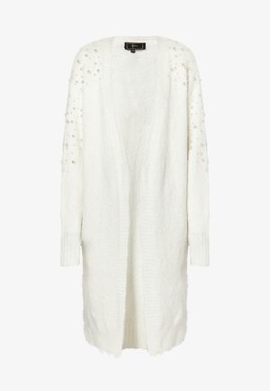 Fehér kardigán, bolyhos anyagból készült, hosszú ujjaival és gyöngyökkel díszítve a vállaknál. Nyitott elülső kialakítás, bordázott mandzsettákkal.