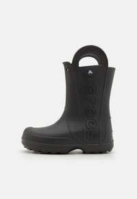 Svart gummistövel med rund tå, texturerad sula, bärhandtag bak och präglad "crocs"-logotyp på sidan.