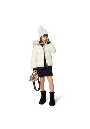 White shiny puffer jacket, black textured skirt, black fur-lined boots, cream knit hat, and a small gold bag with a graphic detail.