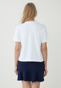 Witte katoenen t-shirt met korte mouwen, voorzien van een ronde hals en een rechte zoom, gecombineerd met een marineblauwe flared rok.