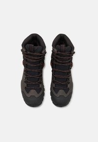 Buty trekkingowe w kolorze szarym i czarnym, z teksturowaną gumową podeszwą, wyściełanym kołnierzem oraz kontrastującymi pomarańczowymi sznurówkami dla pewnego dopasowania.