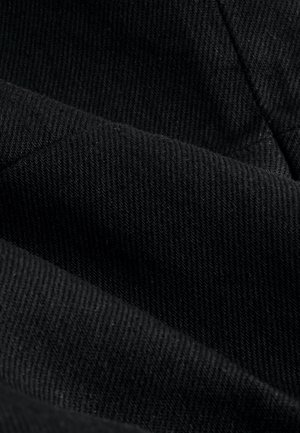 Svart tyg med tät ribbad struktur, som visar olika nyanser och subtil färgdjup, med en slät yta och mjuk finish.