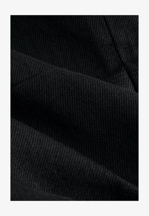 Svart tyg med tät ribbad struktur, som visar olika nyanser och subtil färgdjup, med en slät yta och mjuk finish.