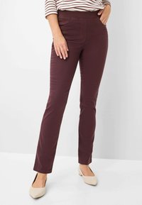 Bordeaux stretchbroek met een slim fit, gladde textuur, elastische tailleband en een voorzak. Draagt met lichtgekleurde, puntige ballerina's.
