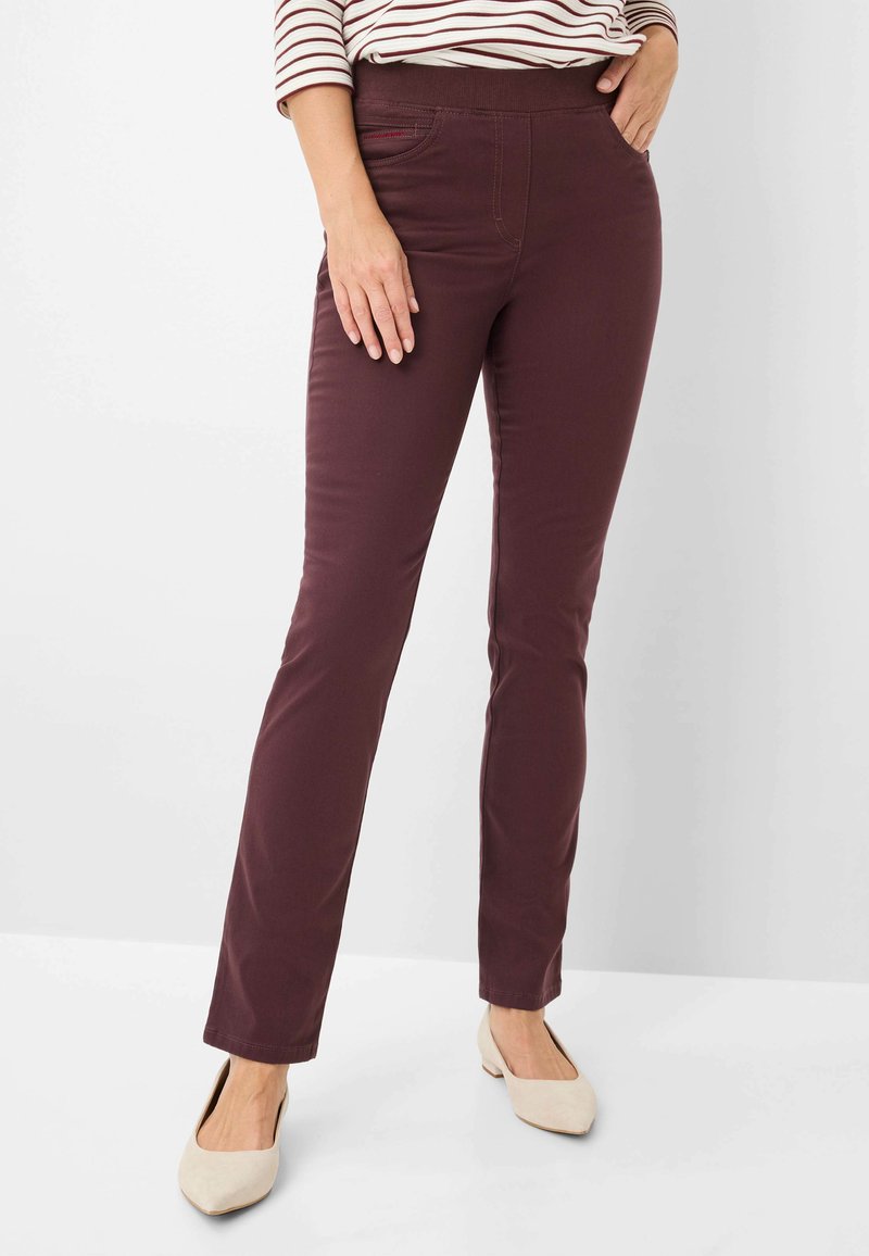 Bordeaux stretchbroek met een slim fit, gladde textuur, elastische tailleband en een voorzak. Draagt met lichtgekleurde, puntige ballerina's.