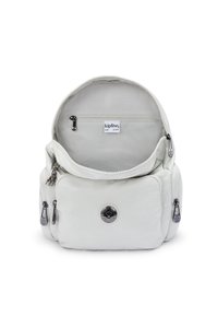 Mochila blanca de nailon con cierre de cremallera, que cuenta con un bolsillo frontal, acentos metálicos y una etiqueta interior. Incluye un pequeño detalle de charm.